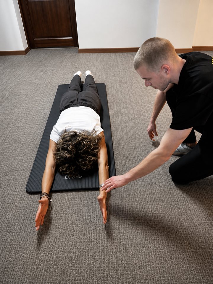Physiotherapeut leitet eine &Uuml;bung auf der Matte an